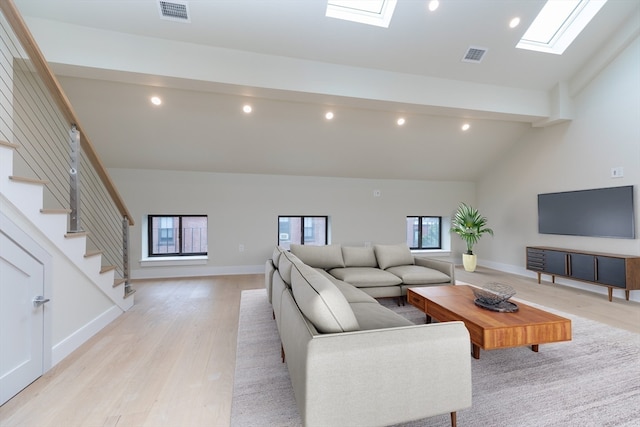 living room featuring high vaulted ceiling, light wood-type flooring, beamed ceiling, and a skylight