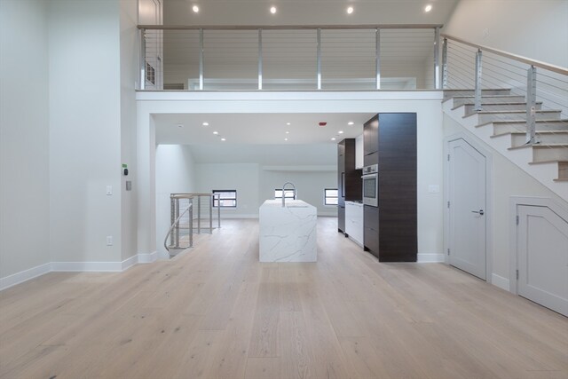 interior space featuring light hardwood / wood-style flooring, sink, and a towering ceiling