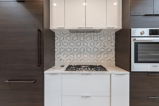 kitchen featuring white cabinets, stainless steel appliances, light stone counters, and decorative backsplash