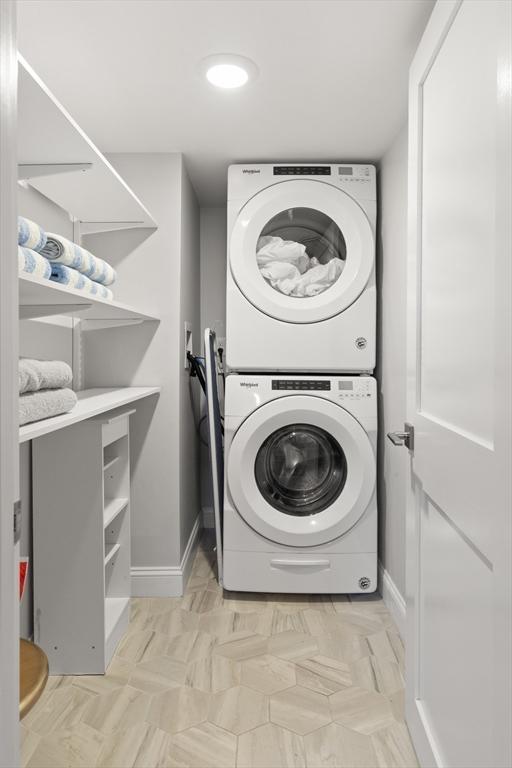 laundry area featuring stacked washer / drying machine, laundry area, and baseboards