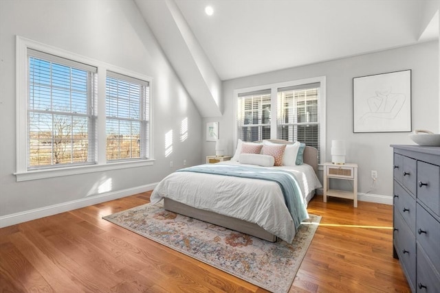 bedroom with lofted ceiling, baseboards, and light wood-style floors