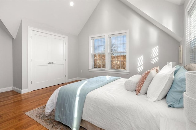 bedroom with lofted ceiling, a closet, baseboards, and wood finished floors