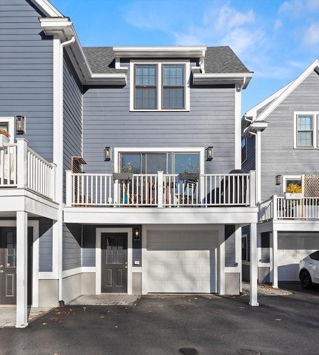 exterior space with a garage, a shingled roof, and aphalt driveway