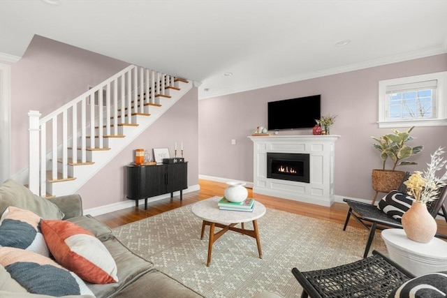 living room with crown molding, stairway, and wood finished floors