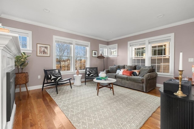 living area featuring light wood-type flooring, a healthy amount of sunlight, baseboards, and ornamental molding