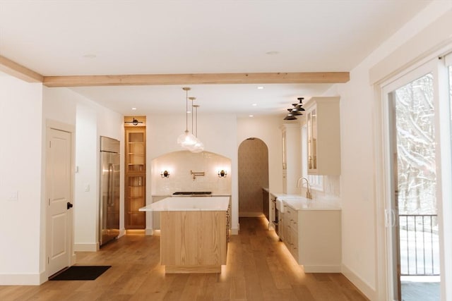 kitchen with ceiling fan, light wood-type flooring, decorative light fixtures, a kitchen island, and stainless steel built in refrigerator