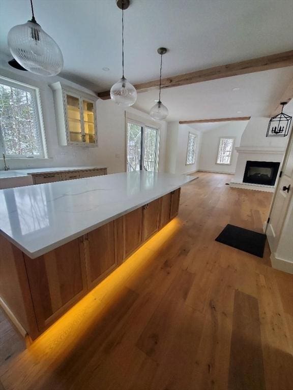 kitchen featuring a kitchen island, light hardwood / wood-style flooring, beamed ceiling, pendant lighting, and white cabinets