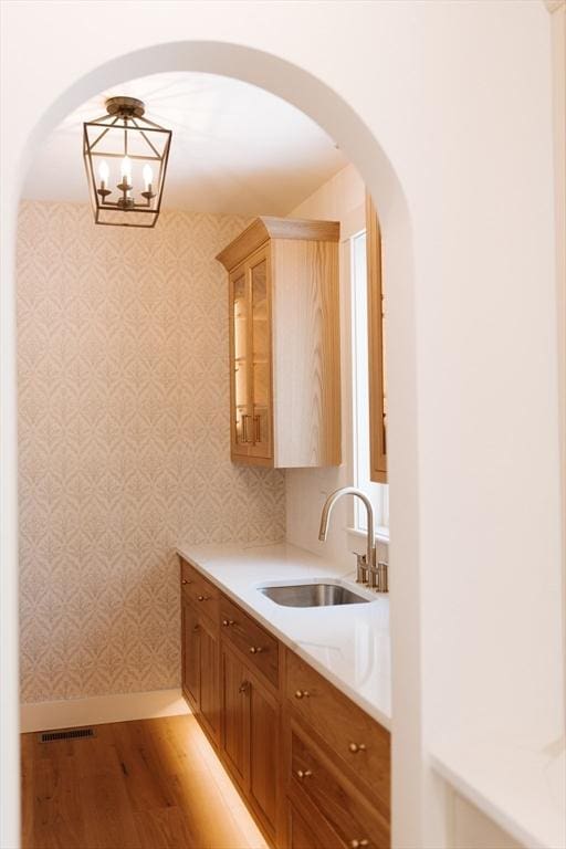 kitchen featuring a chandelier, sink, hanging light fixtures, and light hardwood / wood-style flooring