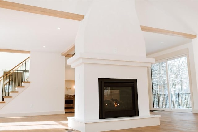 room details with a multi sided fireplace, hardwood / wood-style floors, and beamed ceiling