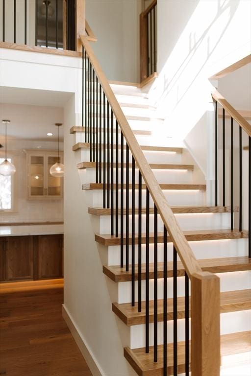 stairway with a high ceiling and hardwood / wood-style flooring