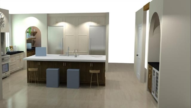 kitchen with a center island with sink, sink, a kitchen bar, range, and stainless steel refrigerator