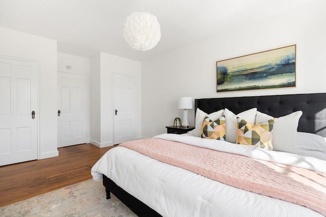 bedroom featuring an inviting chandelier, wood finished floors, and baseboards