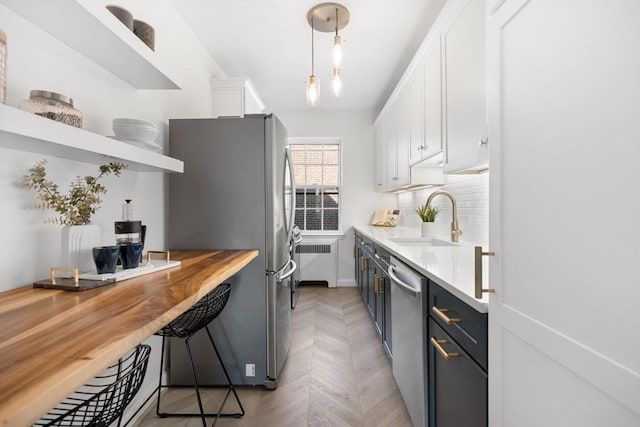 kitchen featuring open shelves, stainless steel appliances, tasteful backsplash, radiator, and a sink