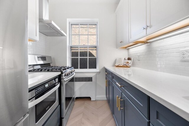 kitchen featuring wall chimney range hood, white cabinetry, appliances with stainless steel finishes, and backsplash