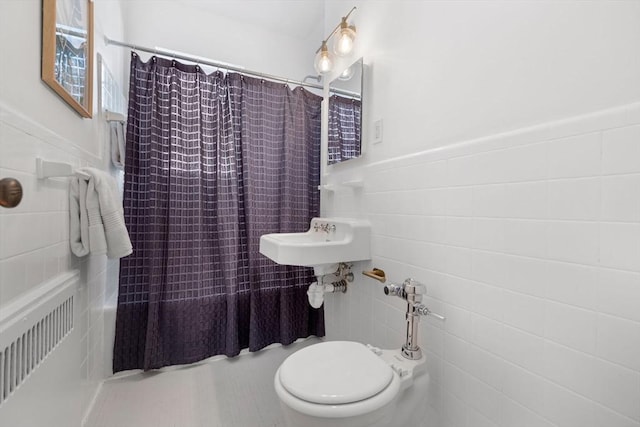 bathroom featuring toilet, a sink, tile walls, and wainscoting