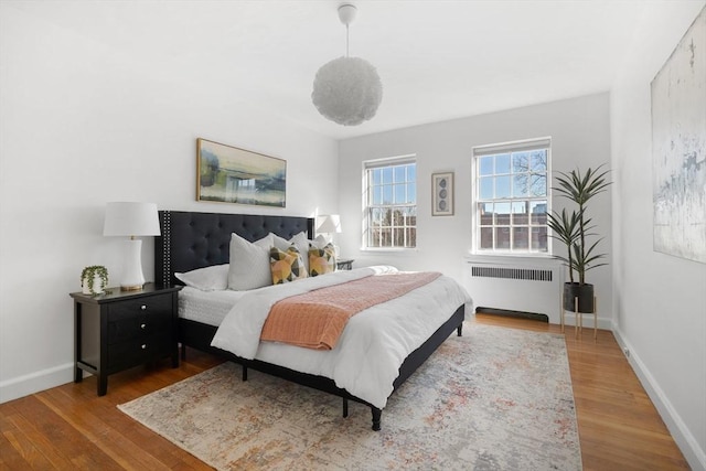 bedroom with radiator heating unit, wood finished floors, and baseboards