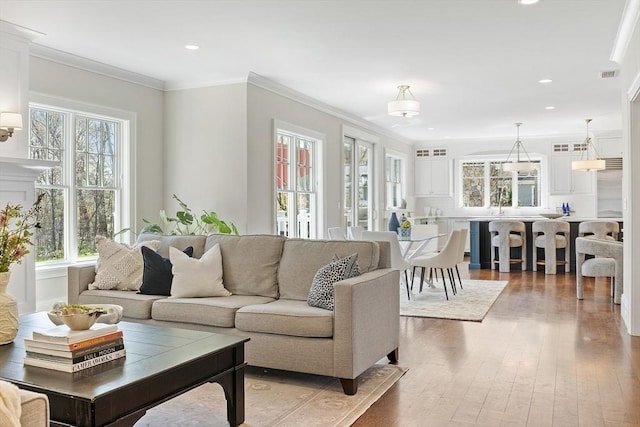 living area with recessed lighting, ornamental molding, visible vents, and hardwood / wood-style flooring