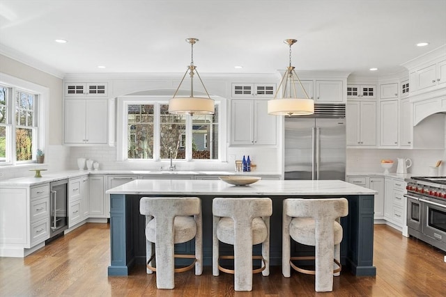 kitchen featuring a breakfast bar area, high quality appliances, a center island, a sink, and wine cooler