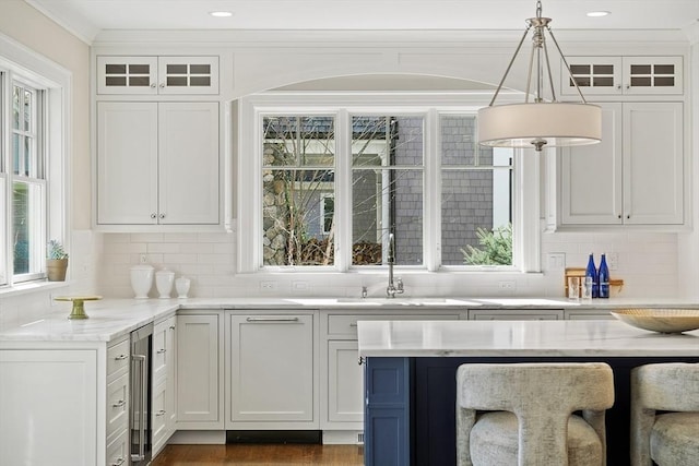 kitchen featuring pendant lighting, glass insert cabinets, plenty of natural light, and backsplash