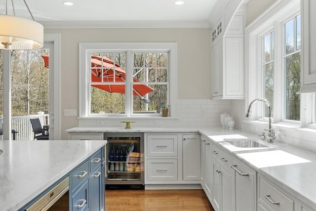 bar featuring wine cooler, ornamental molding, light wood finished floors, and a sink