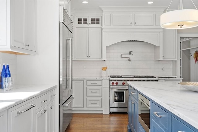 kitchen with built in appliances, white cabinetry, tasteful backsplash, and blue cabinets