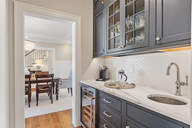 bar with ornamental molding, wine cooler, a sink, wet bar, and light wood finished floors