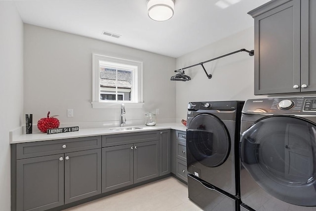 washroom with visible vents, a sink, cabinet space, and washer and dryer