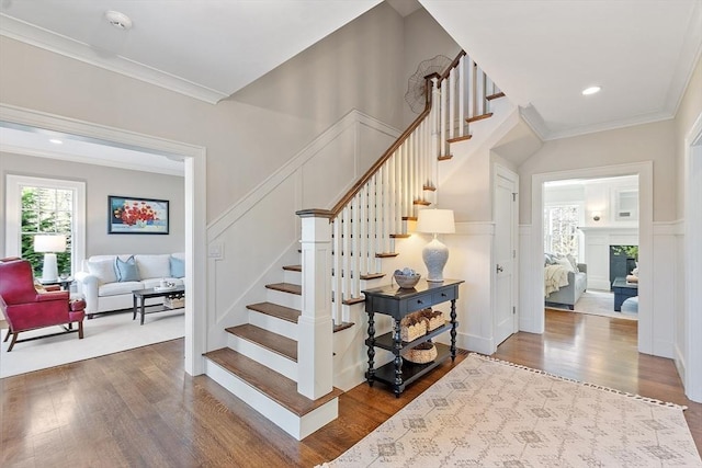 staircase featuring ornamental molding, wood finished floors, and a decorative wall