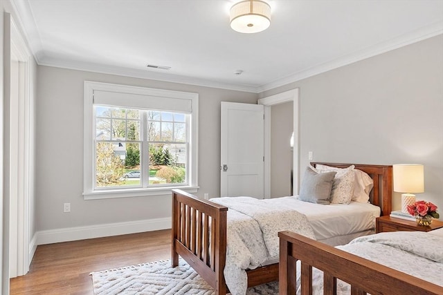 bedroom with baseboards, visible vents, ornamental molding, and light wood finished floors
