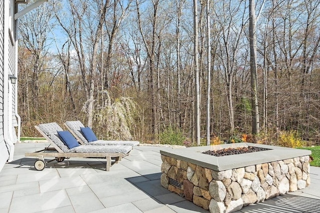 view of patio featuring a view of trees and a fire pit