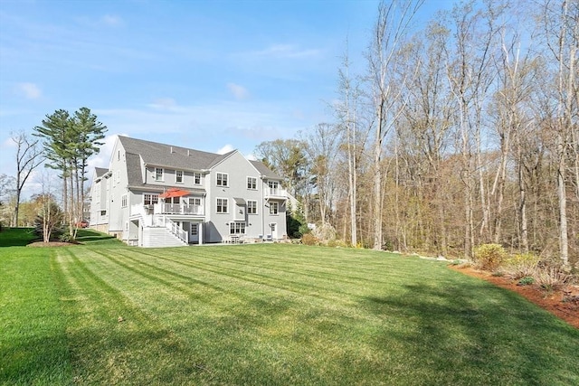 back of property with stairs, a lawn, and a deck