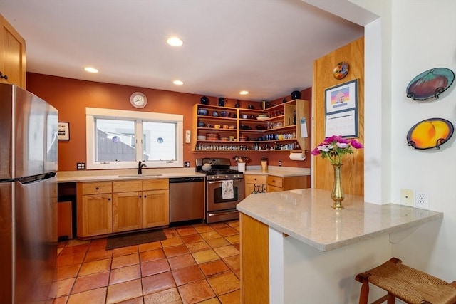 kitchen with appliances with stainless steel finishes, a sink, a peninsula, open shelves, and a kitchen breakfast bar
