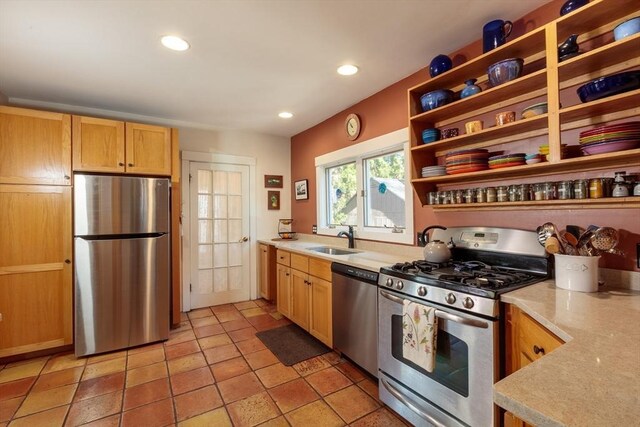 kitchen featuring stainless steel appliances, light countertops, a sink, recessed lighting, and open shelves