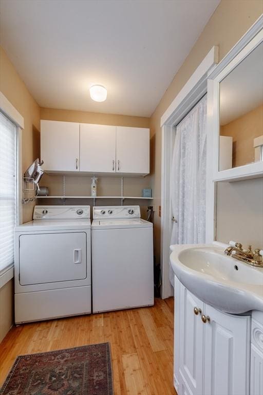 washroom with washing machine and clothes dryer, a sink, and light wood finished floors