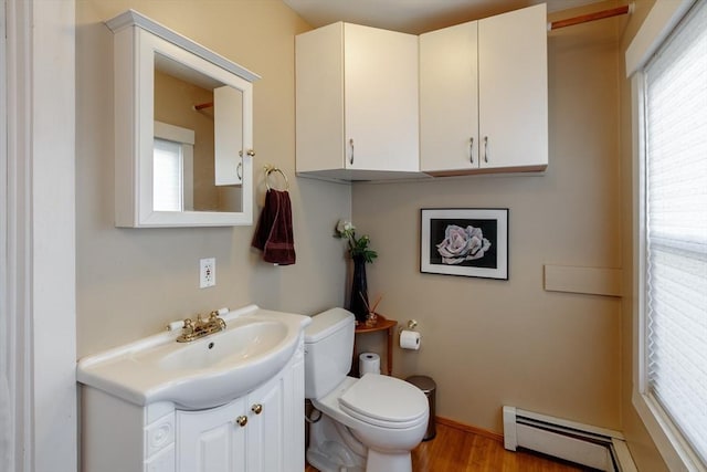 half bath featuring healthy amount of natural light, a baseboard radiator, toilet, and vanity