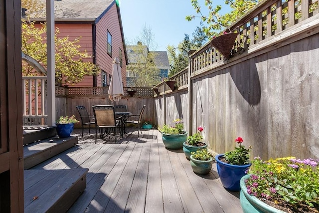 wooden deck with outdoor dining space and a fenced backyard