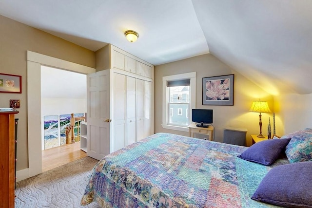 bedroom with carpet flooring, lofted ceiling, and a closet