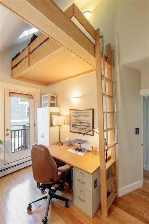 office space featuring light wood-type flooring, a baseboard radiator, and baseboards