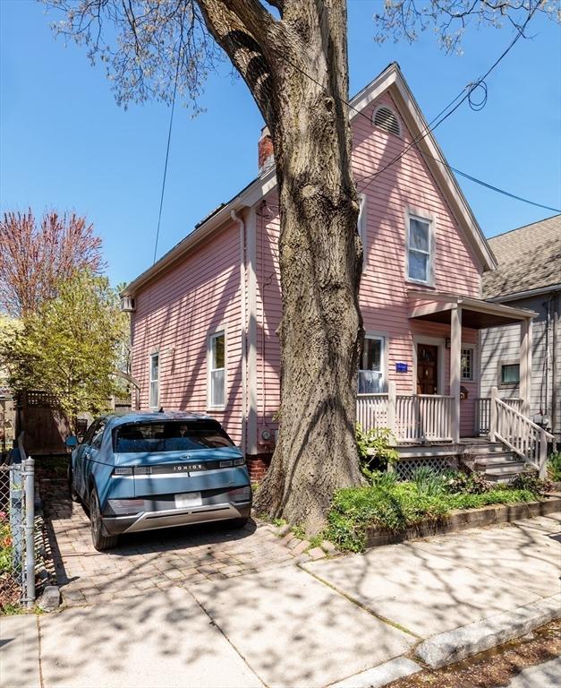 view of side of home with a chimney, a porch, and concrete driveway
