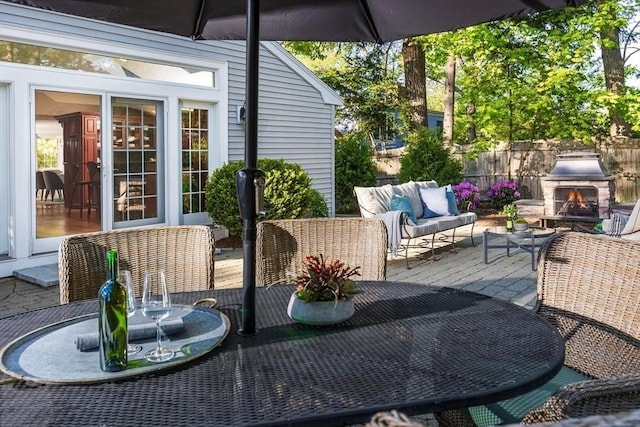 view of patio with an outdoor living space with a fireplace, outdoor dining area, and fence