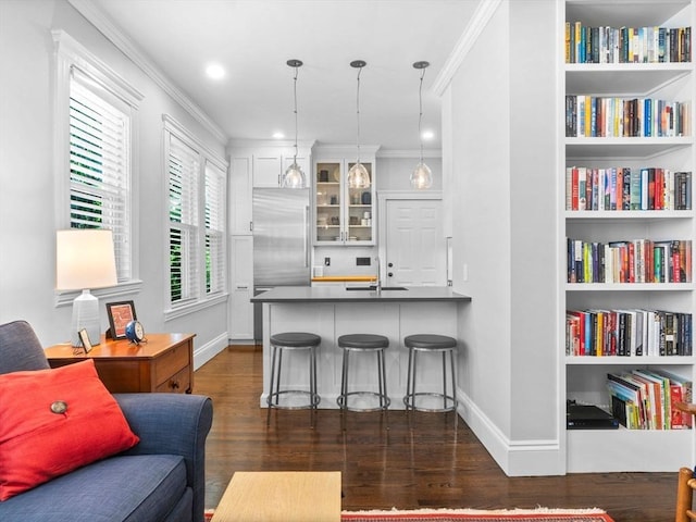 9 Sedgwick St Unit 1, Boston, MA 02130 - kitchen featuring dark wood finished floors, crown molding, glass insert cabinets, a peninsula, and a kitchen bar