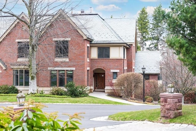 tudor house with brick siding and a high end roof