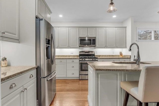 kitchen featuring light hardwood / wood-style flooring, stainless steel appliances, light stone countertops, pendant lighting, and sink