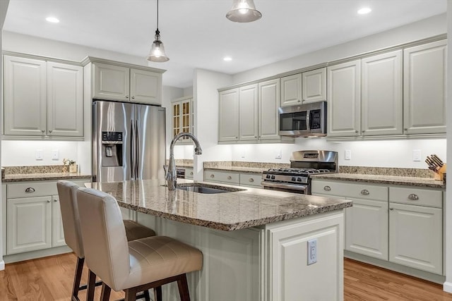 kitchen with a center island with sink, light hardwood / wood-style flooring, sink, and stainless steel appliances