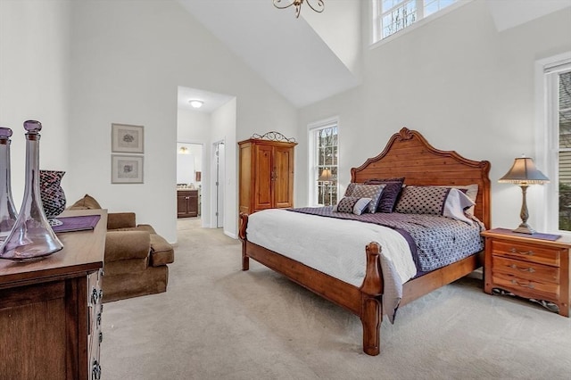 bedroom with multiple windows, high vaulted ceiling, ensuite bathroom, and light colored carpet