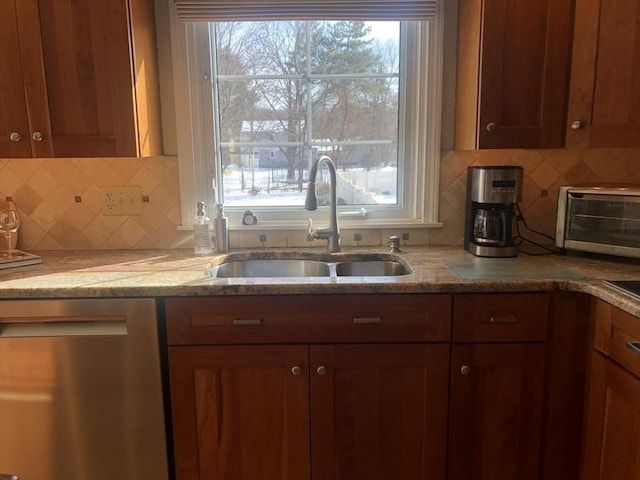 kitchen with a wealth of natural light, brown cabinets, dishwasher, and a sink