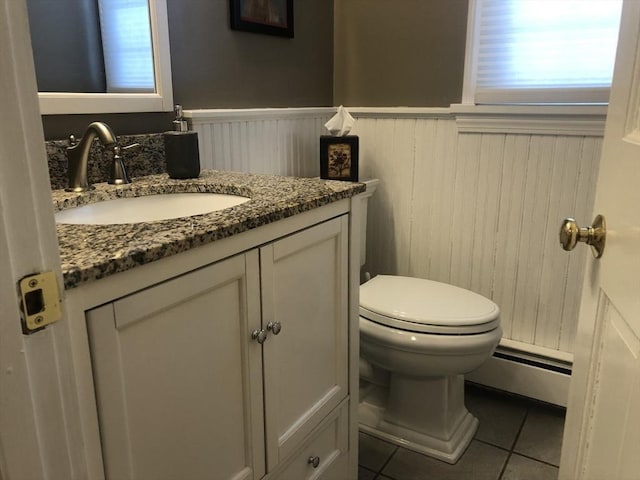 half bathroom featuring a wainscoted wall, a baseboard radiator, tile patterned flooring, and vanity