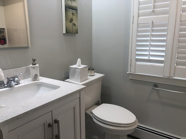 half bathroom with a baseboard radiator, vanity, and toilet