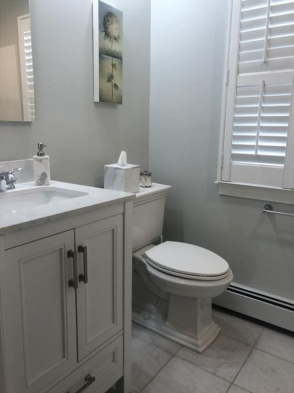 half bathroom featuring a baseboard heating unit, vanity, and toilet