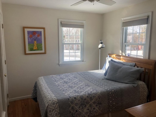 bedroom with a ceiling fan, multiple windows, baseboards, and wood finished floors